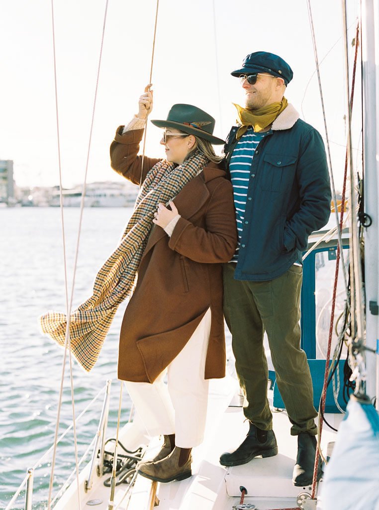 a couple pose for their engagement photos at Newport Beach on a boat as they look out over the water by DC wedding photographer Kim Branagan