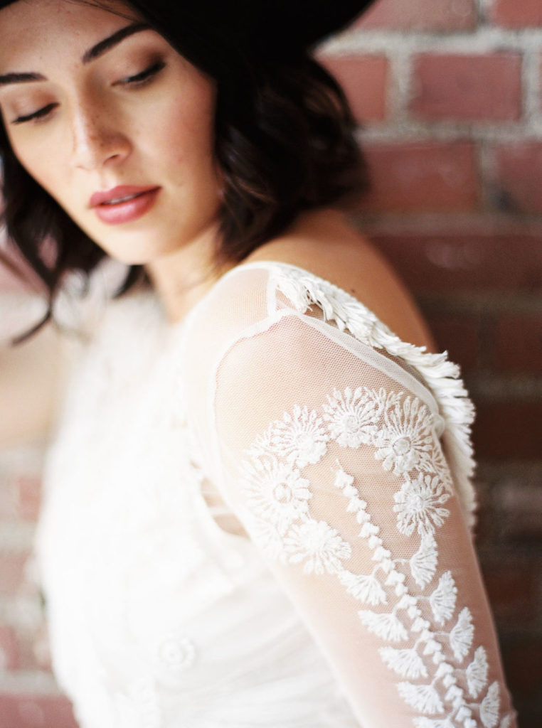 Woman looking down and wearing long-sleeved white lace wedding gown at a Minimalist Bridal Editorial Shoot by Virginia photographer Kim Branagan