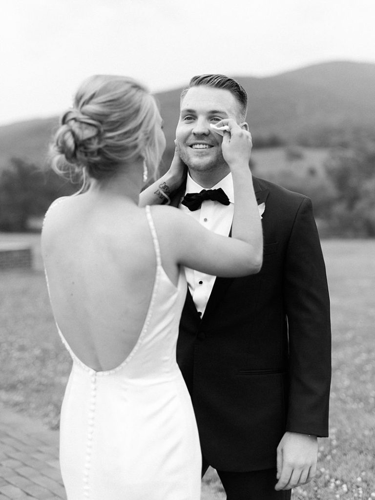 A bride wipes a tear from her grooms eye as he smiles at her