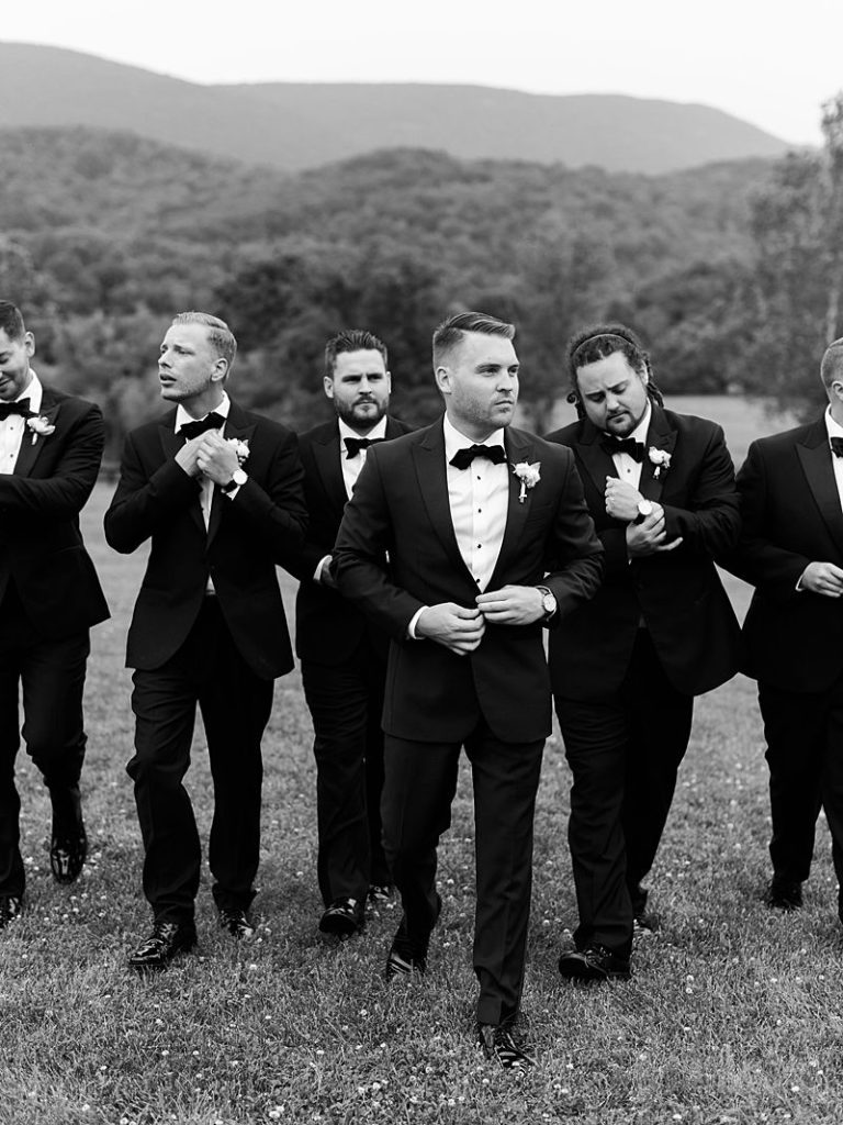 A groom and his groomsmen adjust their attire as they walk towards the camera during a wedding at King Family Vineyards in Charlottesville, VA.
