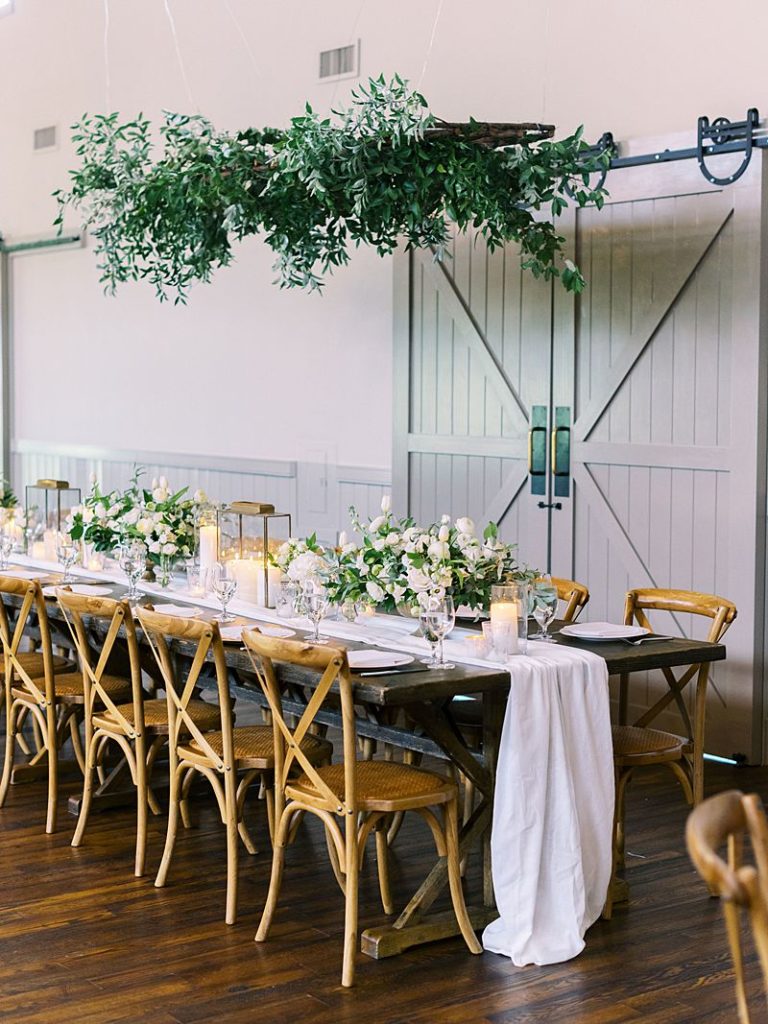 a long table with a white runner and wedding flowers and wooden chairs sits in a room at King Family Vineyards. Photographed by Virginia wedding photographer Kim Branagan.