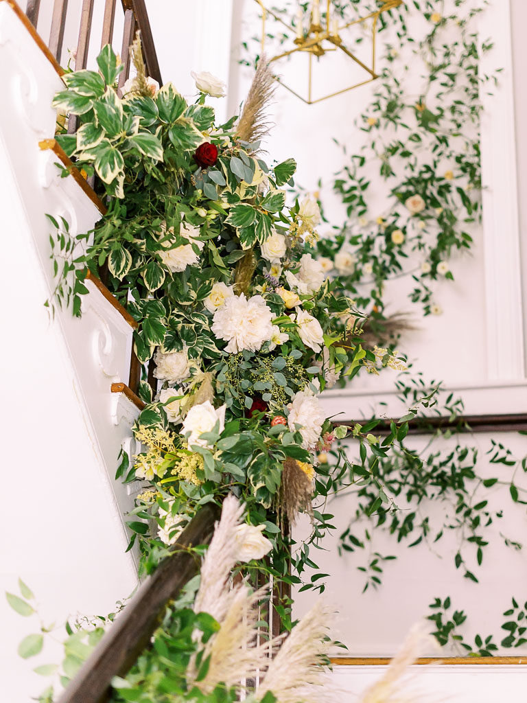 Greenery and light yellow flowers against a white wall and by a flight of stairs by wedding photographer Kim Branagan
