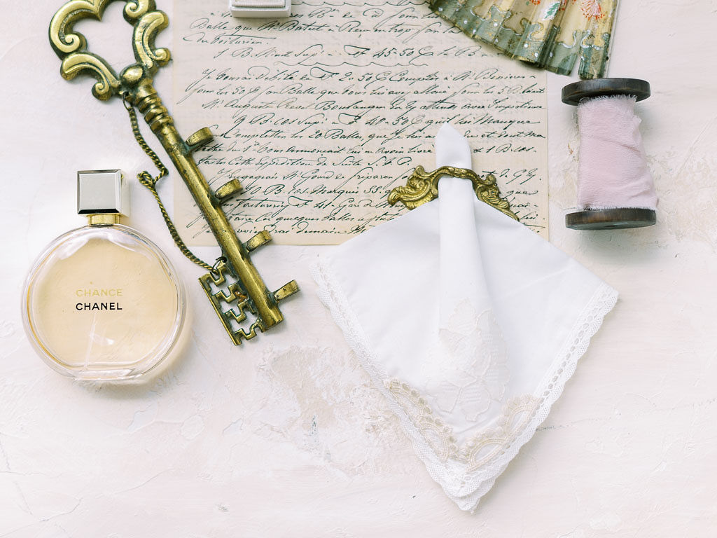 Various objects from a wedding day at Antrim 1844: Chanel perfume, a large gold key, an embroidered handkerchief, and a handwritten letter.