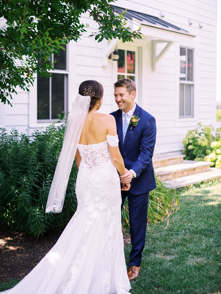 A bride and groom stand outside, holding hands and smiling at each other on their wedding day. Photo by northern Virginia wedding photographer Kim Branagan