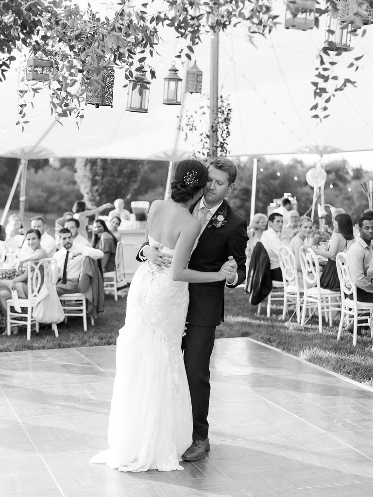 A bride and groom slow dance on the dance floor on their wedding day. Lanterns and cascading greenery hang above them. Photo by Virginia and Washington D.C. wedding photographer Kim Branagan.