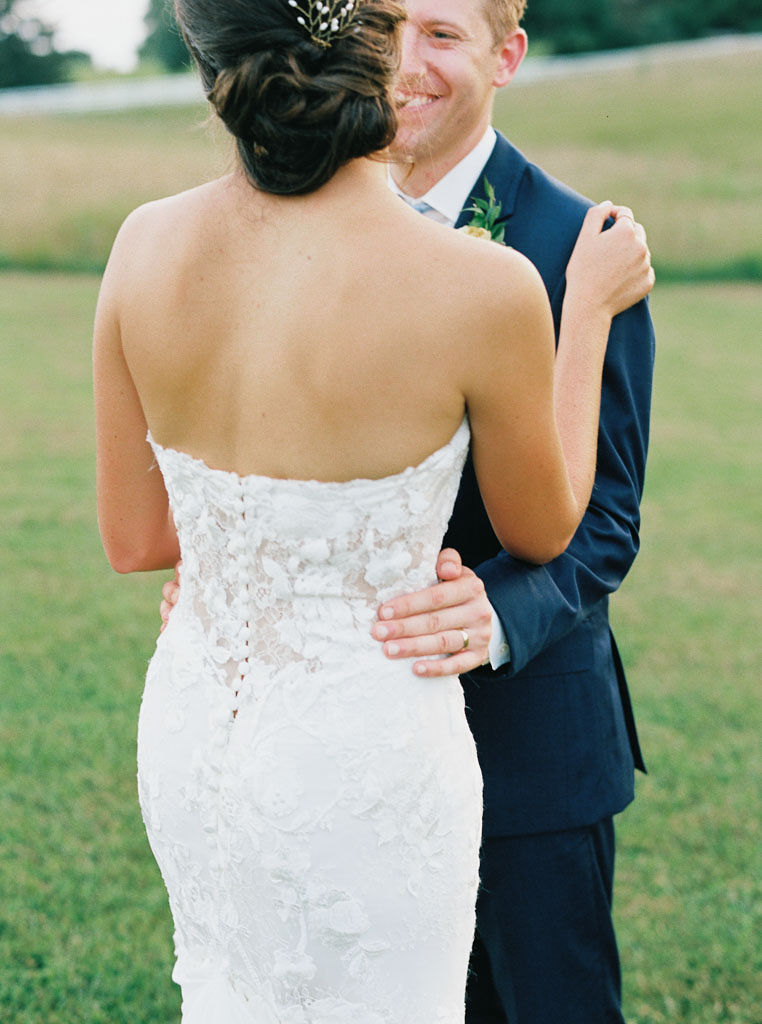 The bride and groom hold each other, directly facing each other. The bride's back is facing the camera.