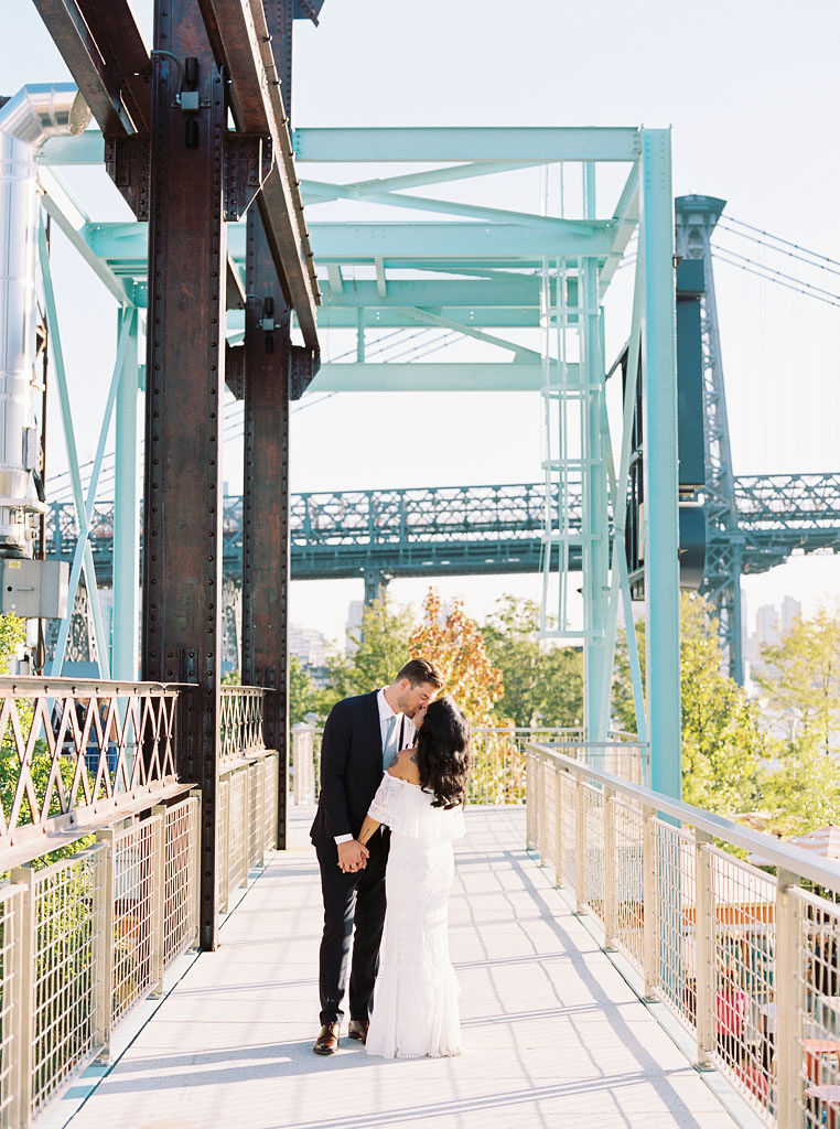 A couple kisses at Domino Park in Williamsburg, New York on their wedding day. Photographed by New York wedding photographer Kim Branagan.