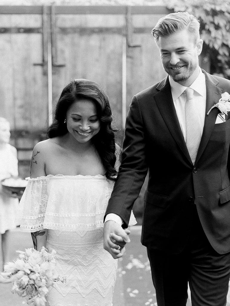 A black and white photo of a couple smiling and walking hand in hand after their wedding ceremony. Photo by Kim Branagan, a New York wedding photographer.