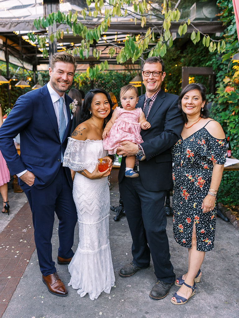 A bride and groom pose with some friends on their wedding day at their outdoor, urban garden venue in Williamsburh, Brooklyn, NY.