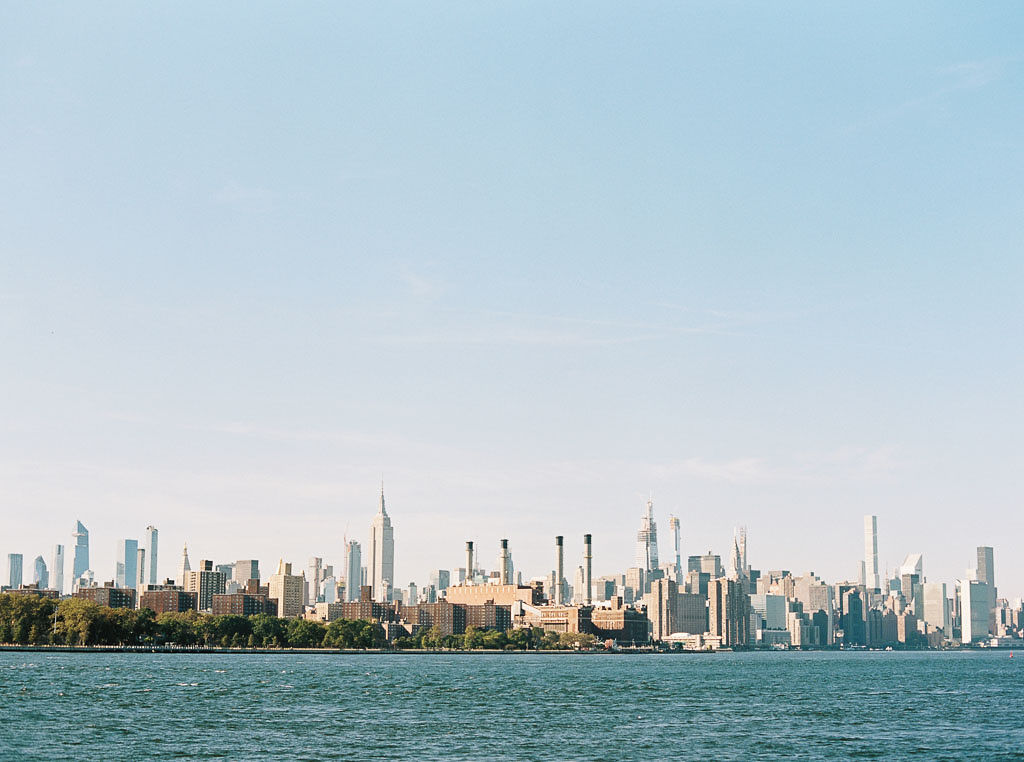 Iconic shot of the Manhattan skyline during the day with a body of water in front of it. Taken by New York photographer Kim Branagan.