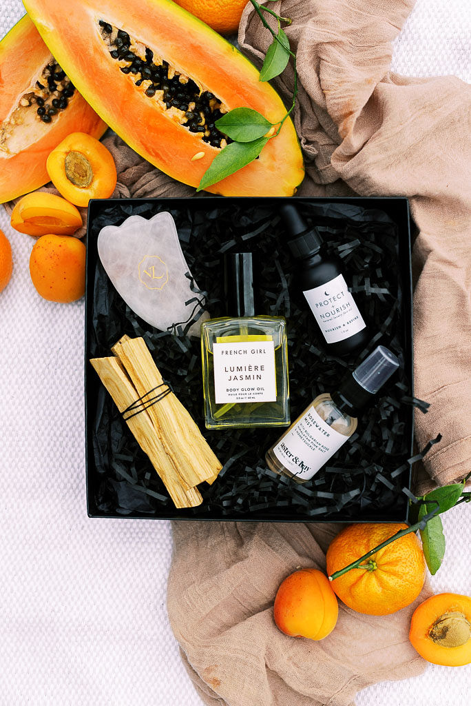 The luxury clean beauty products in Verde Lusso's summer beauty box on a mauve picnic blanket, surrounded by summer citrus fruits. Photographed by east coast branding photographer Kim Branagan.