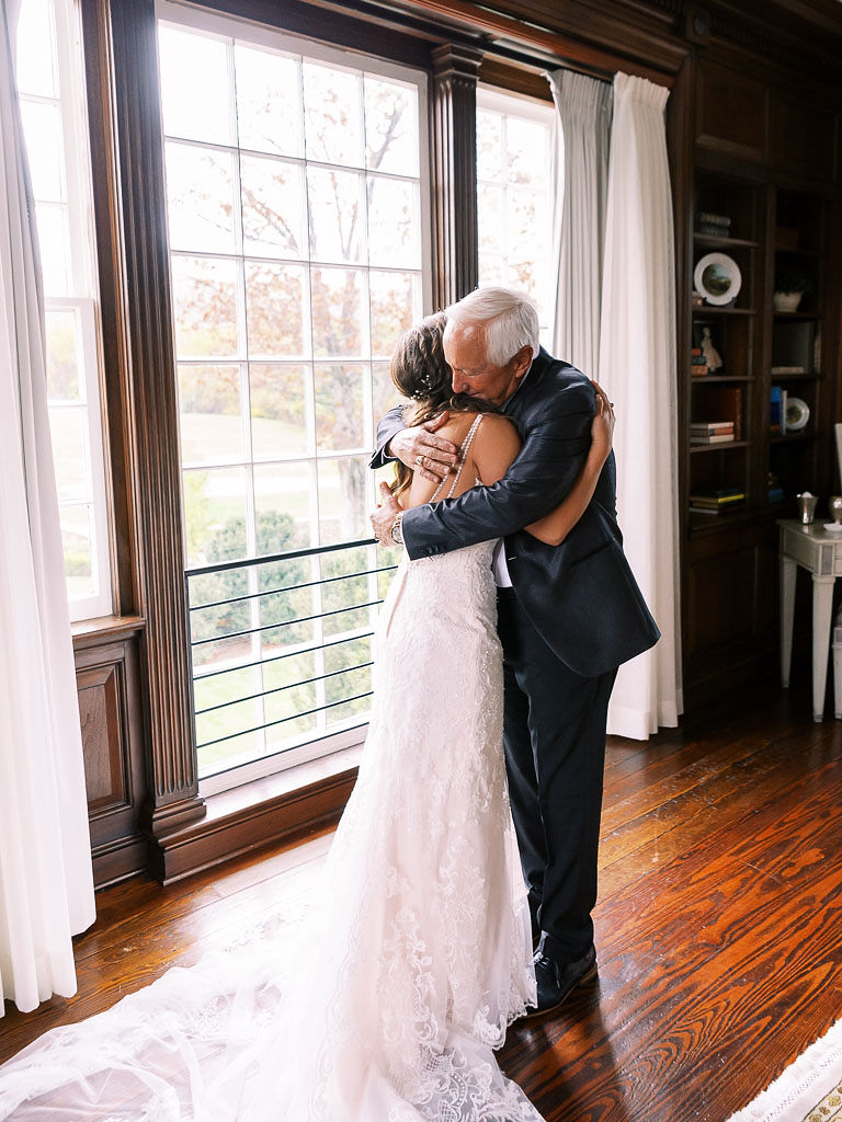 A bride and her father hug on her wedding day before the ceremony