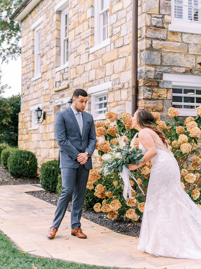 A bride walking toward her groom on their wedding day for their first look before the ceremony. The groom has just opened his eyes and is seeing his bride for the first time. Photographed by Virginia wedding photographer Kim Branagan.
