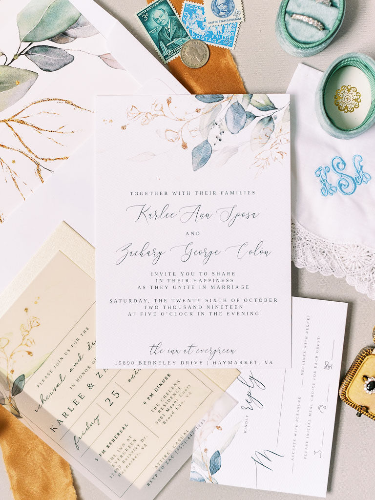 The couple's wedding invitations, save the date cards, and wedding bands on a table.