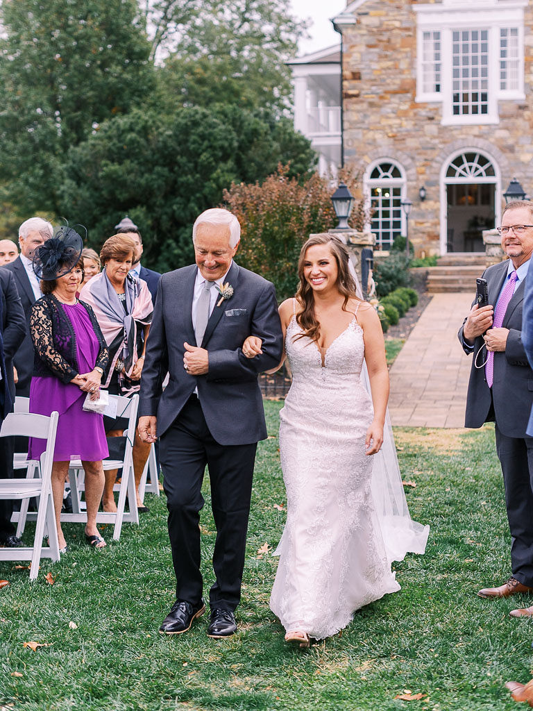 A bride being walked down the aisle by her father at her wedding. Photographed by northern Virginia wedding photographer Kim Branagan.