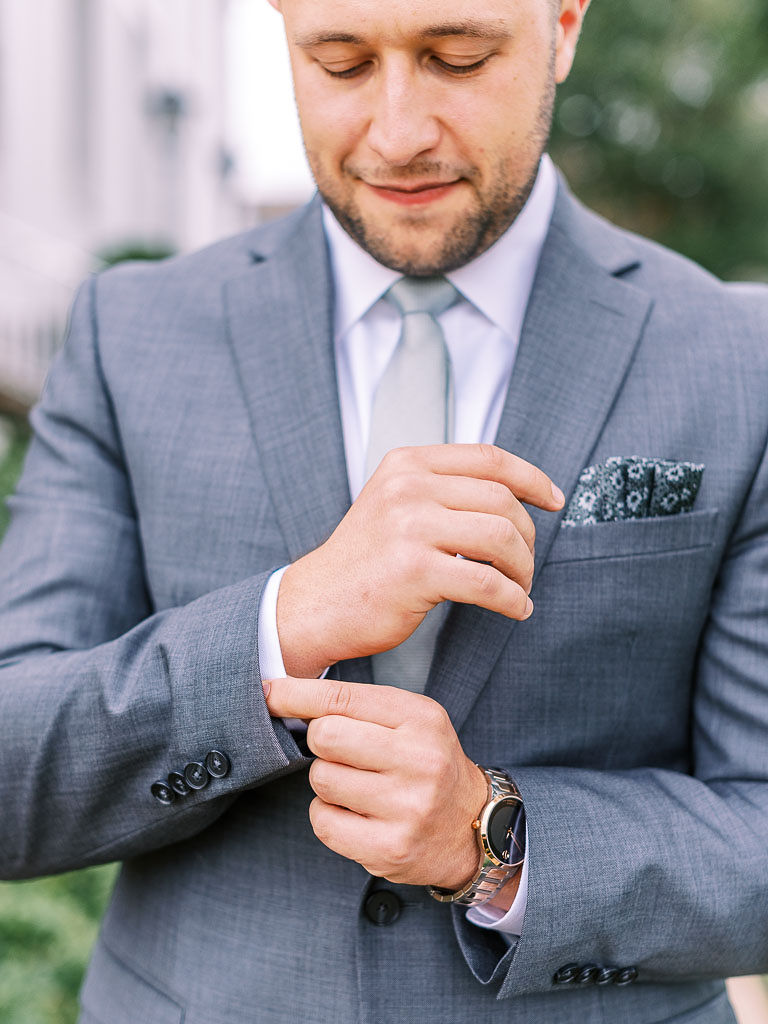 A man buttoning his shirt on his wedding day.