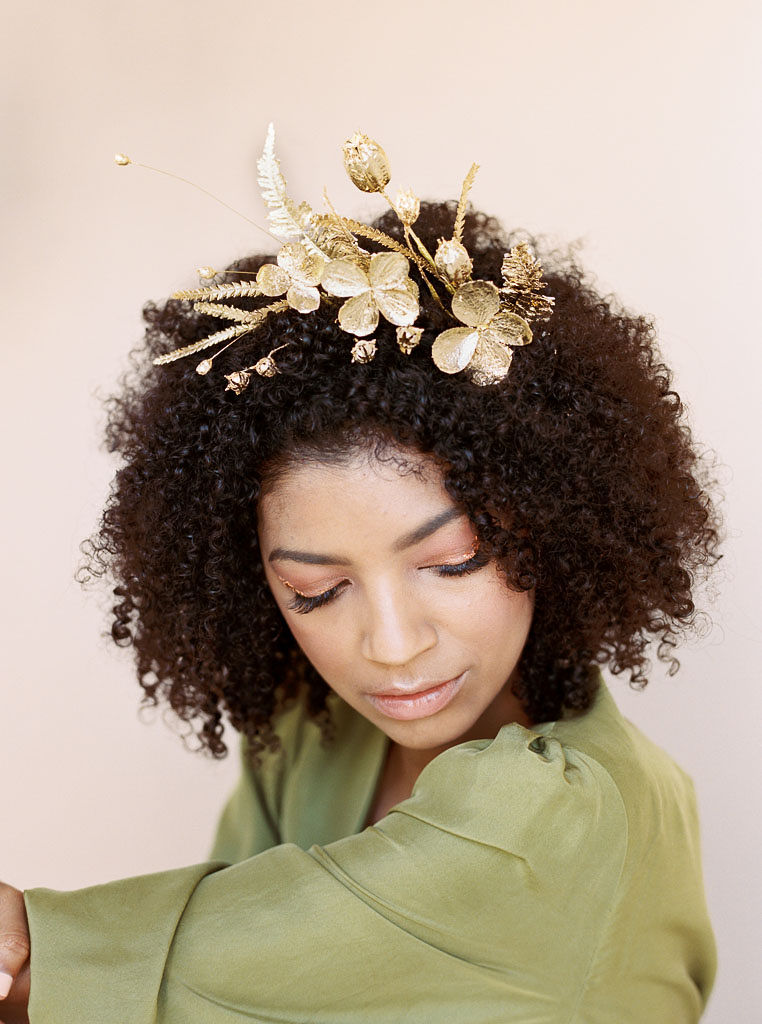 Close up shot of a model at a branding editorial photo shoot looking down at the ground with a golden floral hair piece in her hair