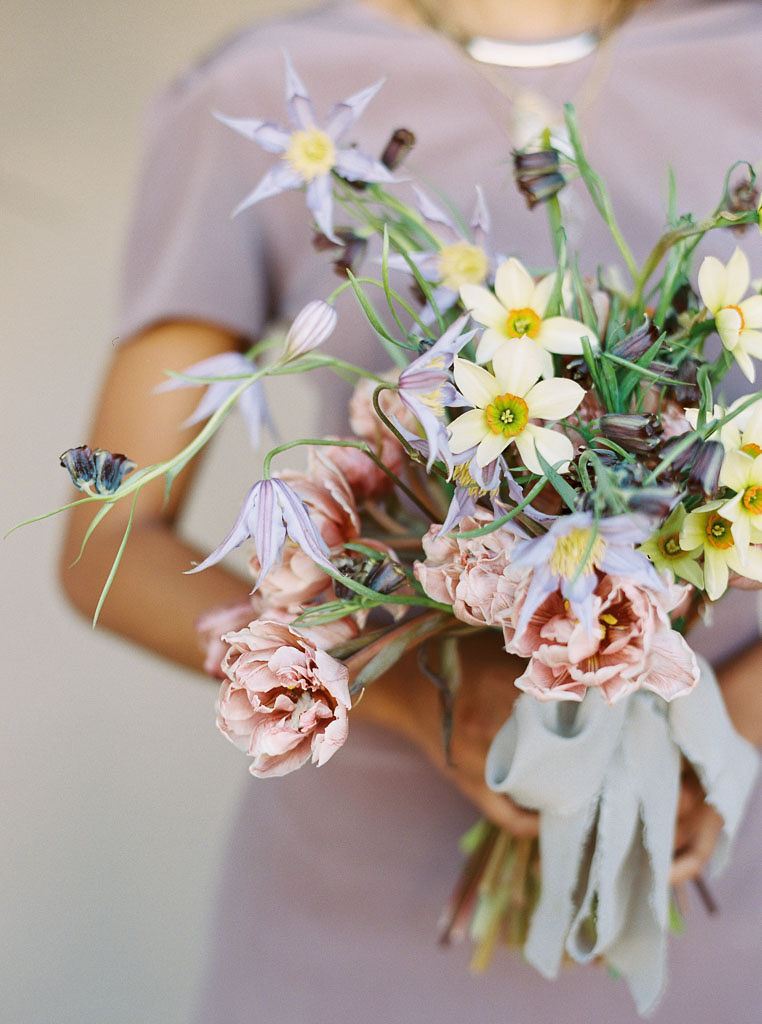 Close up of a bouquet of white and pink flowers tied together with a pale blue ribbon.