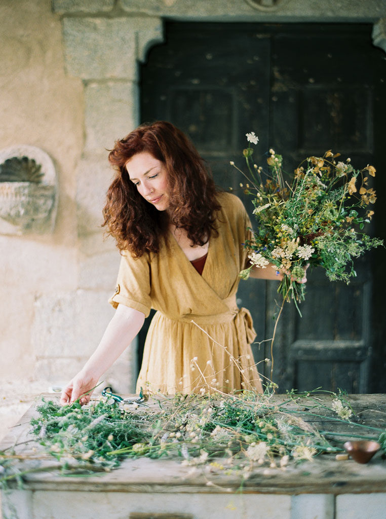 A woman holds a bouquet of flowers as she designs a floral arrangement. Clarity Retreat - A Floral Workshop by Ponderosa & Thyme | Florence, Italy. Photographed by Florence brand and editorial photographer Kim Branagan.