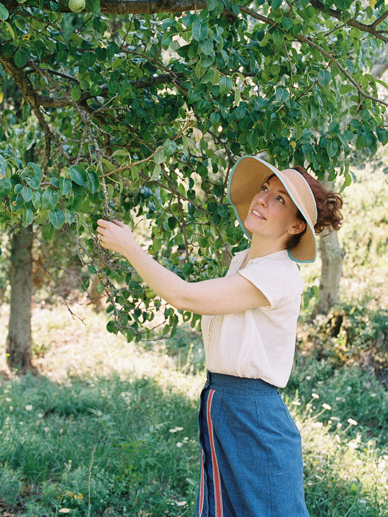 A woman touches leaves on a tree. Clarity Retreat - A Floral Workshop by Ponderosa & Thyme | Florence, Italy. Photographed by Florence brand and editorial photographer Kim Branagan.