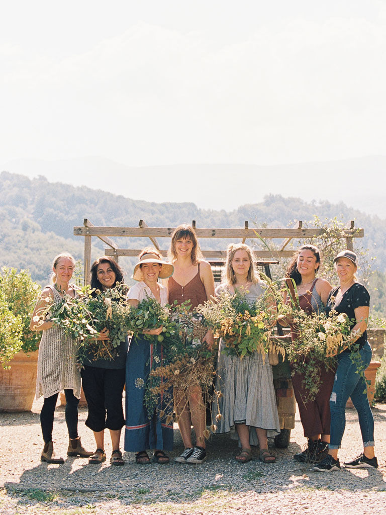 Women stand in a row on the grounds of Castello di Potentino, holding the flowers and foliage they found on the property. Clarity Retreat - A Floral Workshop by Ponderosa & Thyme | Florence, Italy. Photographed by Florence brand and editorial photographer Kim Branagan.