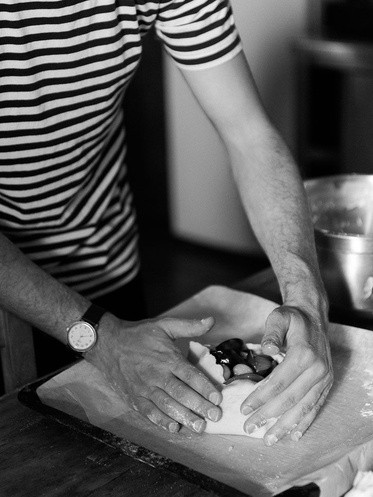 Black and white, close up shot of a man preparing food in a kitchen.Clarity Retreat - A Floral Workshop by Ponderosa & Thyme | Florence, Italy. Photographed by Florence brand and editorial photographer Kim Branagan.