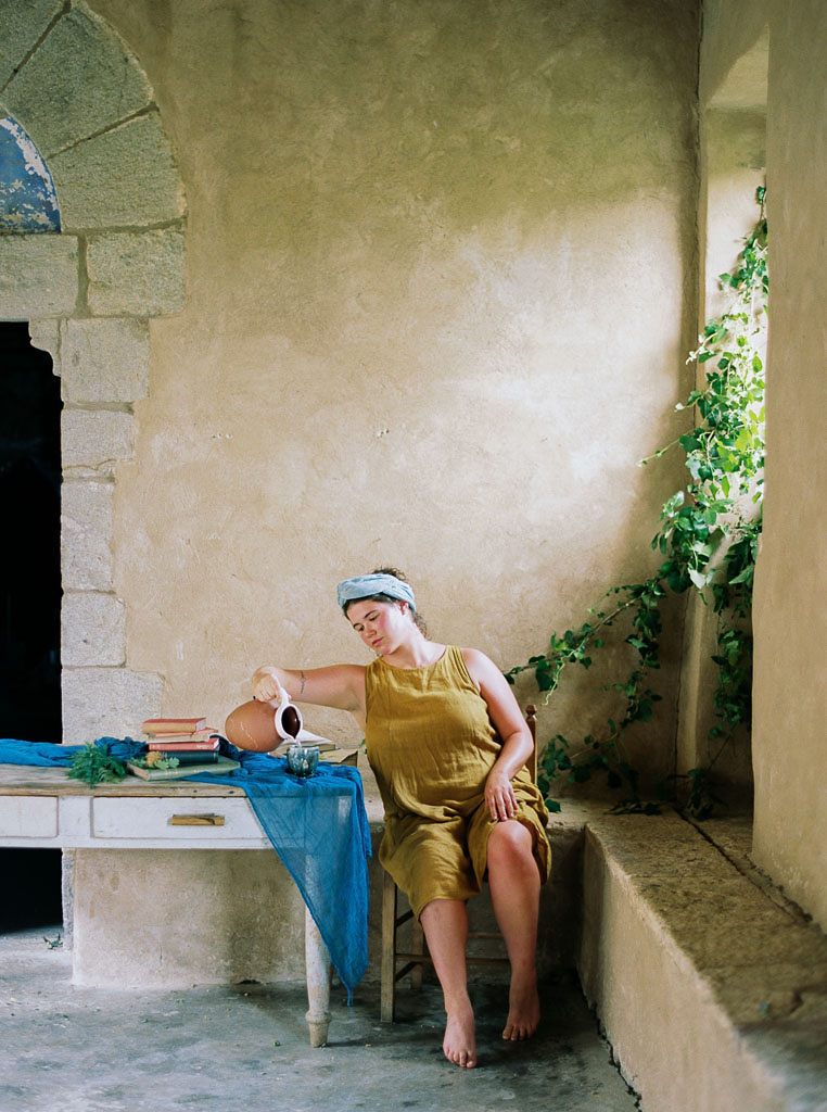 A woman sitting in a chair in an Italian villa pouring herself a glass of water. Clarity Retreat - A Floral Workshop by Ponderosa & Thyme | Florence, Italy. Photographed by Florence brand and editorial photographer Kim Branagan.