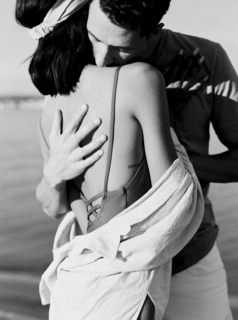 A black and white photo of a couple hugging closely. Destination Photoshoot for a Lifestyle Editorial on the Beach in San Diego, CA by San Diego lifestyle editorial photographer Kim Branagan
